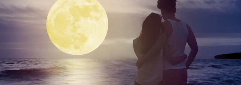 Couple Standing in the Ocean Looking at the Strawberry Full Moon